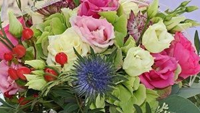 Ein farbenfroher Blumenstrauß auf einem Tisch mit Gläsern im Hintergrund