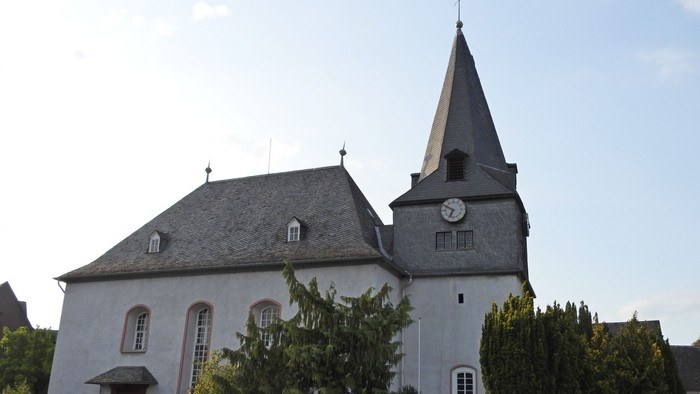 Kleine Kirche mit Uhrturm und grünem Gestrüpp