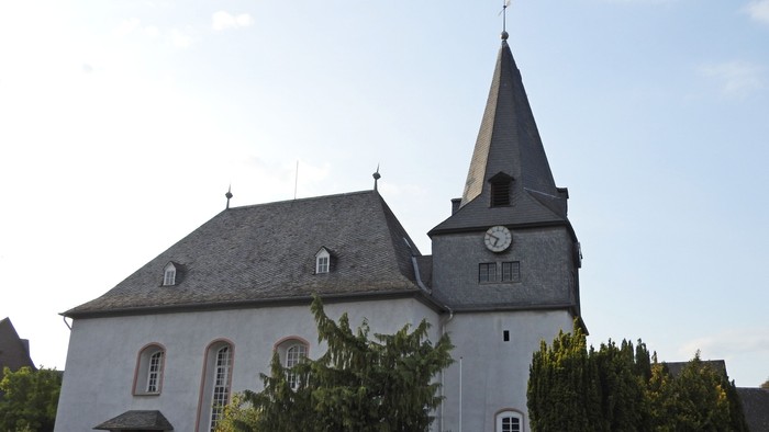Kleine Kirche mit Uhrturm und grünem Gestrüpp