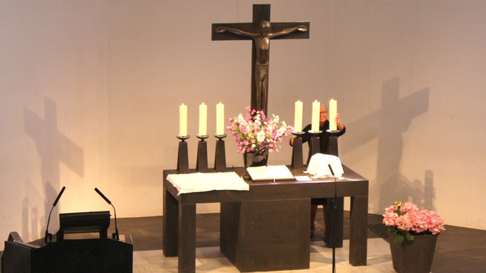 Ein Altar mit Kreuz, Kerzen und Blumen in einem Kirchenraum