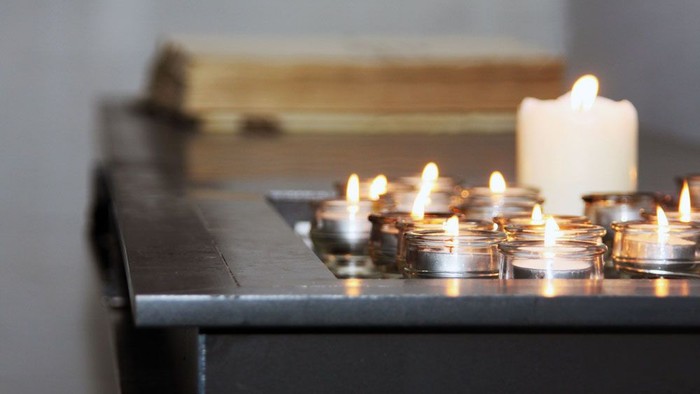 Mehrere brennende Teelichter auf einem schwarzen Tisch