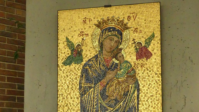 Mosaikikone der Jungfrau Maria mit dem Jesuskind und Engeln, darunter ein kerzenbeleuchteter Schrein.