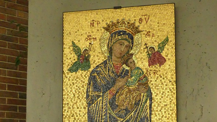 Mosaikikone der Jungfrau Maria mit dem Jesuskind und Engeln, darunter ein kerzenbeleuchteter Schrein.