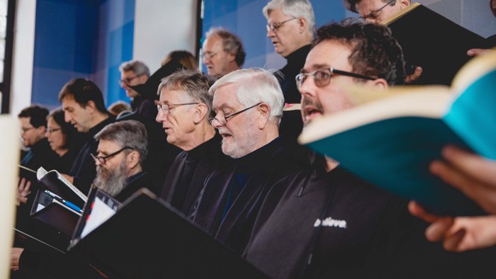 Eine Gruppe von Männern mit Laptops und Büchern in einem Raum.