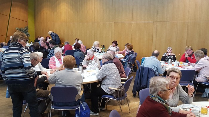 Eine Gruppe älterer Menschen sitzt an Tischen und isst.