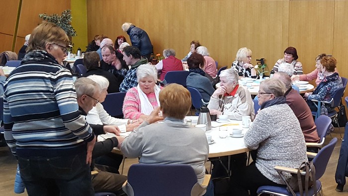 Eine Gruppe älterer Menschen sitzt an Tischen und isst.