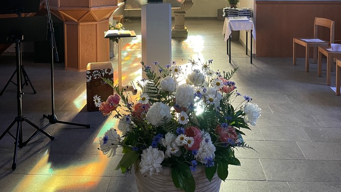 Blumenstrauß vor Kirchenfenster mit Kreuzdarstellung