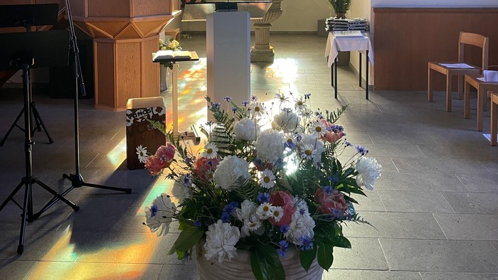 Blumenstrauß vor Kirchenfenster mit Kreuzdarstellung