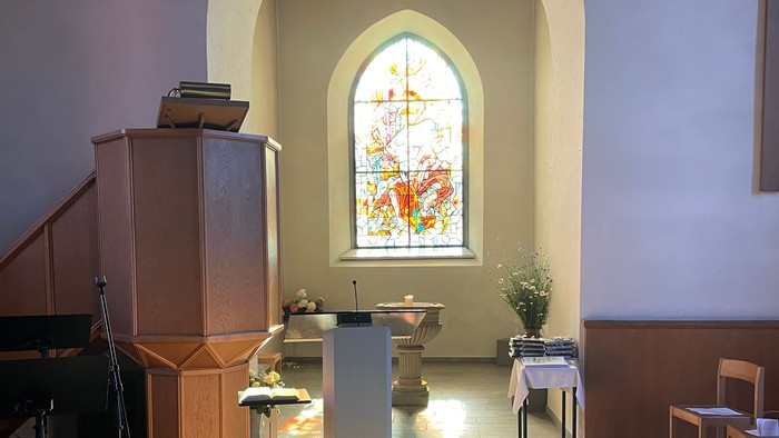 Blumenstrauß vor Kirchenfenster mit Kreuzdarstellung