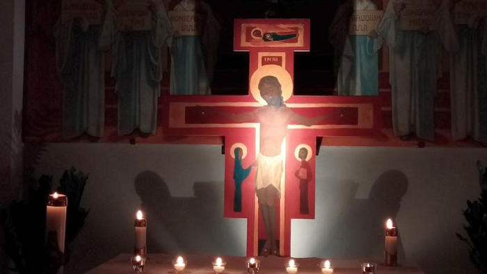 Religiöse Altarszene mit beleuchteten Statuen und brennenden Kerzen während einer nächtlichen Zeremonie.