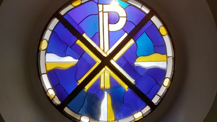 Farbenfrohes Buntglasfenster mit christlichem Symbol in Kirche