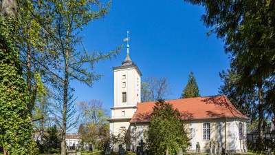 Weiße Kirche mit hohem Turm und rotem Dach im grünen Park