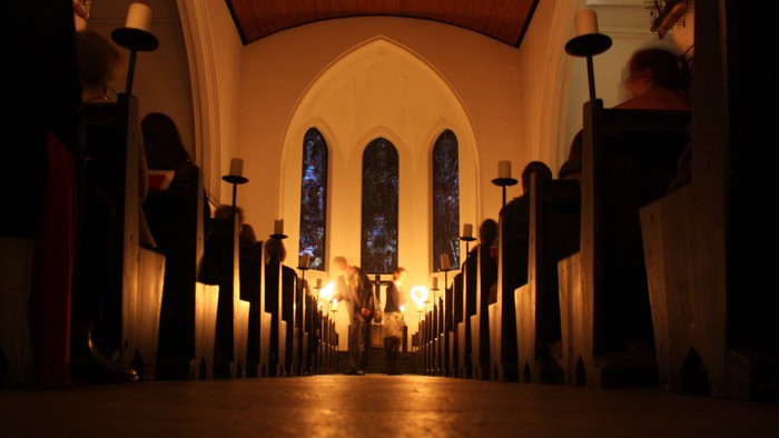 Kirchengang mit brennenden Kerzen, Kirchenfenster im Hintergrund