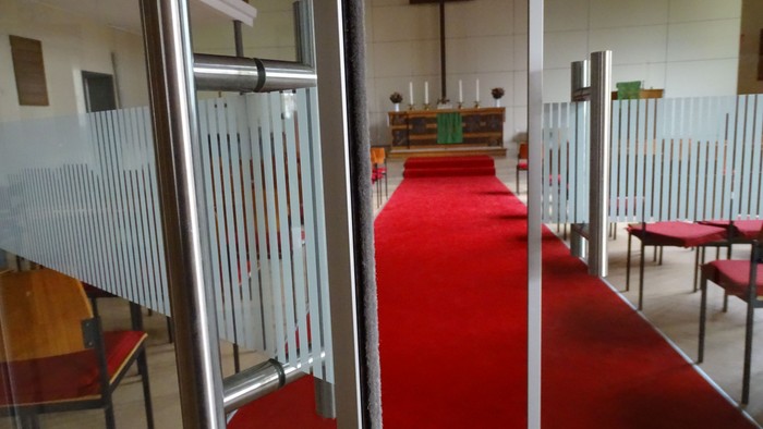 Kirchlicher Raum mit rotem Teppich und Holzbänken