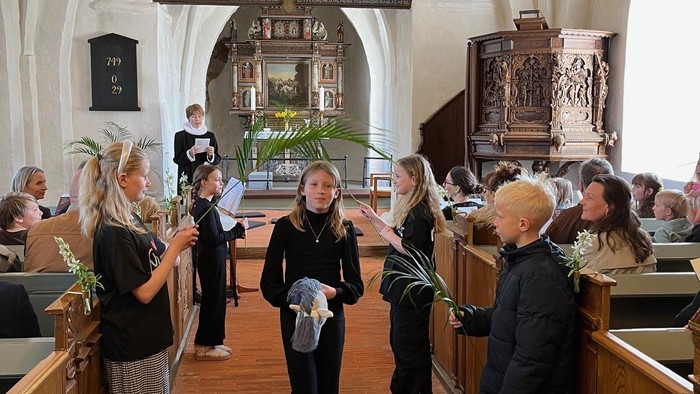 Mennesker i en kirkegang, der holder blomster under en ceremoni eller sammenkomst.