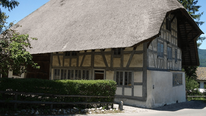 Das Bild zeigt ein traditionelles Fachwerkhaus mit Reetdach und gepflegtem Garten.
