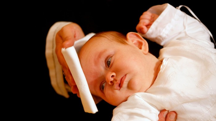 Et spæd barn holder en tandbørste foran sit ansigt.