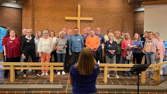 En gruppe af mennesker samlet i kirke med præst ved alteret