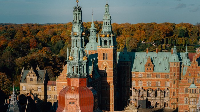 Storslået historisk palads omgivet af efterårsagtig skov og indviklede arkitektoniske detaljer.