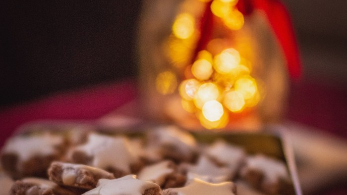 Weihnachtliche Plätzchen in einer Dose und eine Kerze
