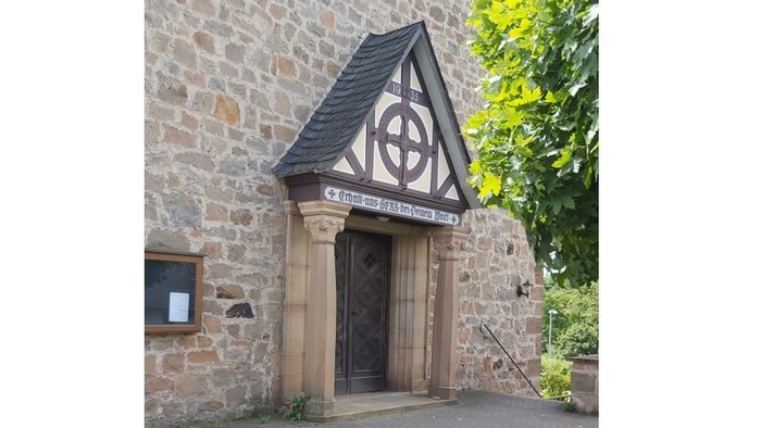 Steingebäude mit Holztür und dreieckigem Dach mit keltischem Design.