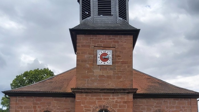 Rotes Backsteingebäude mit einem Turm und Rundbogenfenstern.