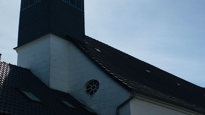 Weiße Kirche mit hohem Turm und spitzem Dach.