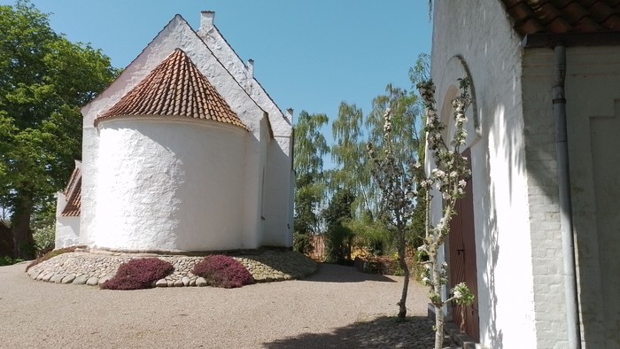 Udsnit af hvid kirke med rødt tag og af hvidt kapel på kirkegården