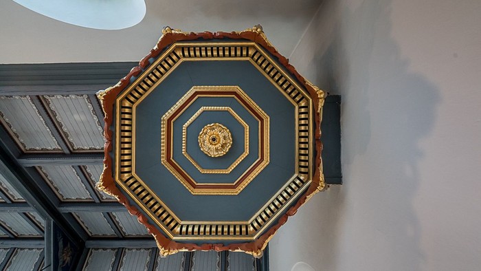 Indretning af væg med oktogonal maleri og guldakcentuer.