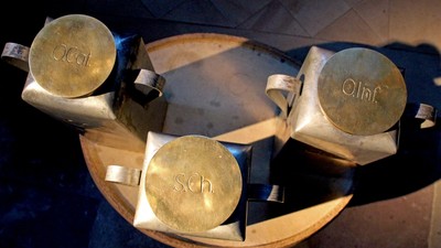 Drei goldfarbene Metallbecher auf einem Tablett