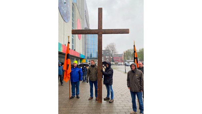 Eine Gruppe von Menschen trägt ein großes Holzkreuz durch die Stadt.
