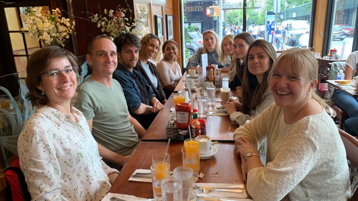 En glad gruppe mennesker, der poserer sammen ved et hyggeligt restaurantbord under et måltid.