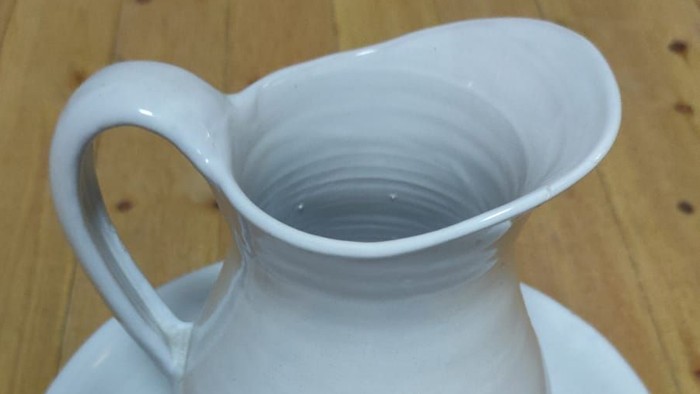 Weißer Krug auf Untertasse auf Holztisch