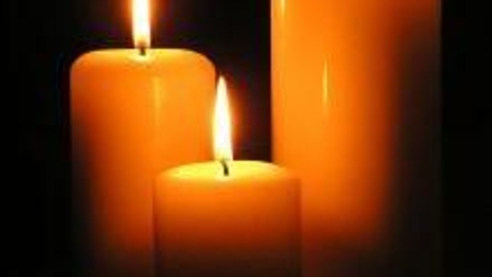 Three lit candles in varying heights against a dark background.