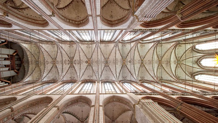 Die Decke einer gotischen Kirche mit aufwendigen Stuckarbeiten und hohen Bögen.