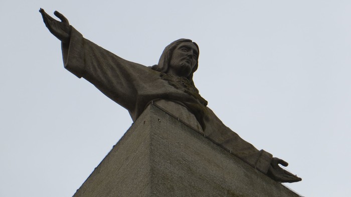 Eine Statue eines Mannes mit ausgebreiteten Armen auf einem Sockel.