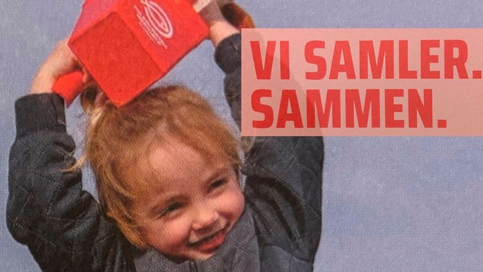 Lille pige holder indsamlingsbøsse til Folkekirkens Nødhjælp med armene strakt over hovedet.