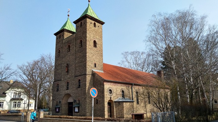 Alte Kirche mit zwei Türmen und rotem Dach an der Straße