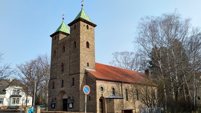 Alte Kirche mit zwei Türmen und rotem Dach an der Straße