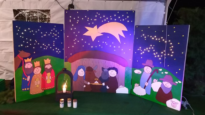 Ein Weihnachtskrippenbild mit Figuren und Kerzen in einer Kirche