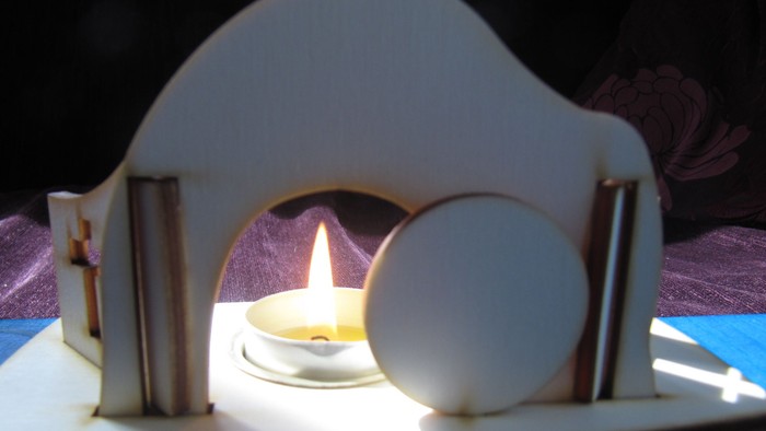 Elegante Miniatur-Kerzenausstellung in einer verspielt weißen, kapellenartigen Holzkonstruktion.