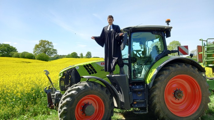 Der Pastor steht auf einem großen Trecker.