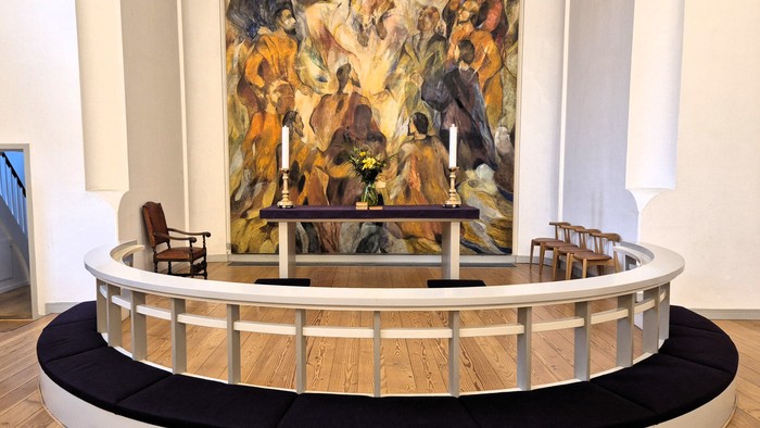 En moderne indretning med stor abstrakt maleri, rund benk og bord med stoler