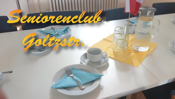 Eine ordentlich gedeckte Tafel bei einer Seniorenclub-Veranstaltung mit Kaffeetassen, Servietten und einer Wasserkaraffe.