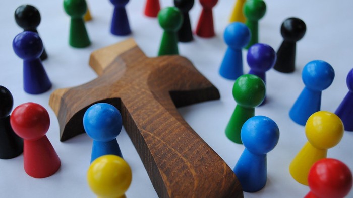 Holzkreuz von bunten Spielsteinen umgeben