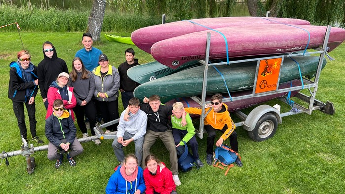 Gruppe von Personen, die mit Kajaks auf einem Anhänger posieren.