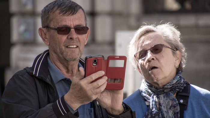 Mann und Frau mit Handy, beide mit Sonnenbrillen