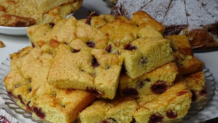 Ein Teller mit verschiedenen Kuchenstücken, darunter ein Kuchen mit Rosinen und ein gefüllter Kuchen.