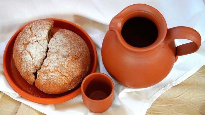 Brot in Tonschüssel und Wein in Tonkrug