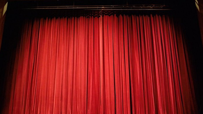 Rote Vorhänge, die eine Bühne bedecken.